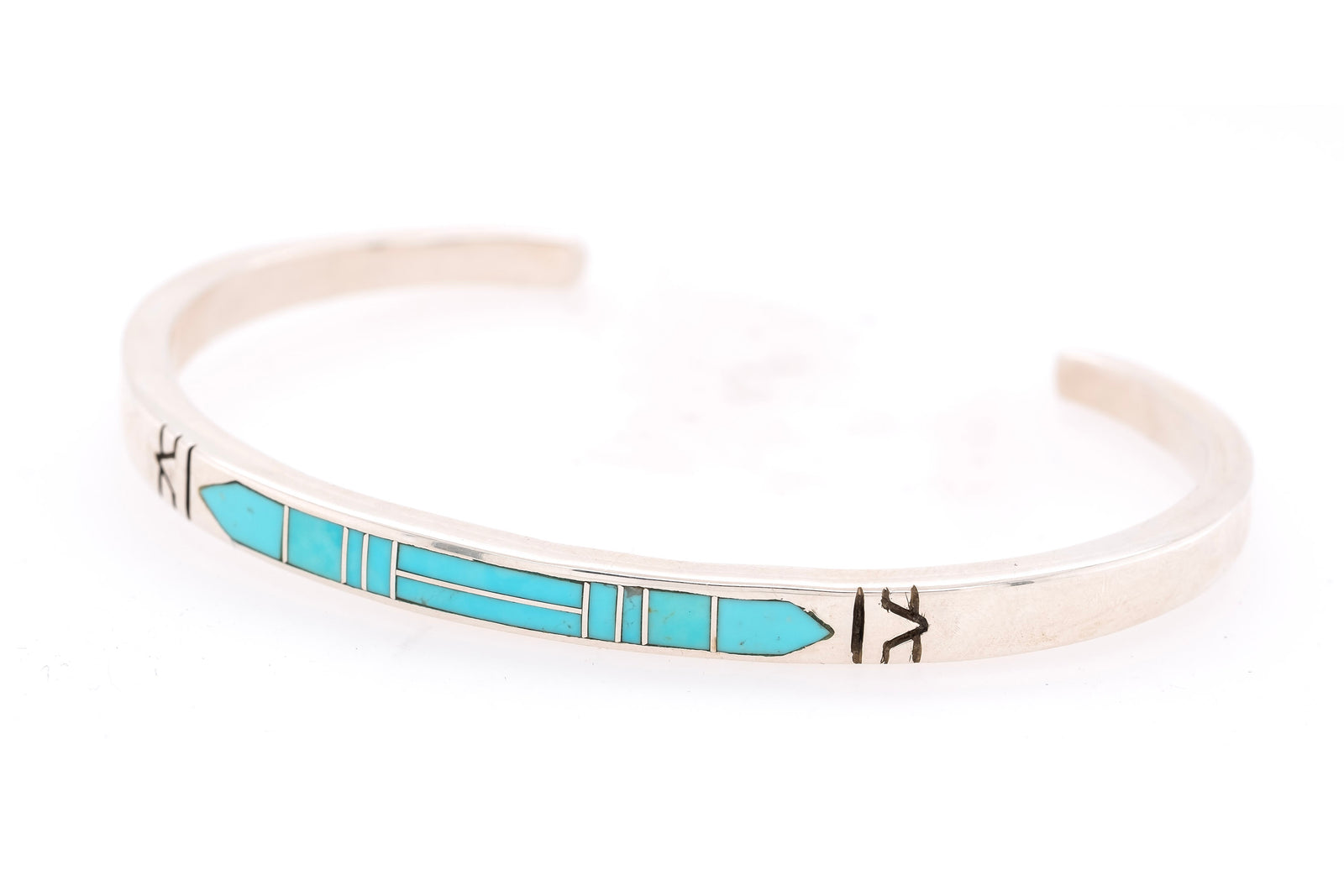 A silver cuff bracelet featuring a turquoise inlay geometric pattern, photographed on a clean white background.