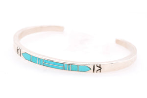 A silver cuff bracelet featuring a turquoise inlay geometric pattern, photographed on a clean white background.
