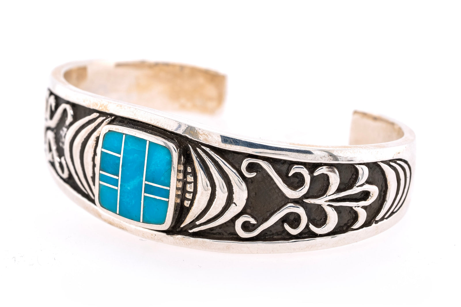 A silver-toned cuff bracelet featuring a turquoise inlay and black oxidized scrollwork details, shown on a plain white background.