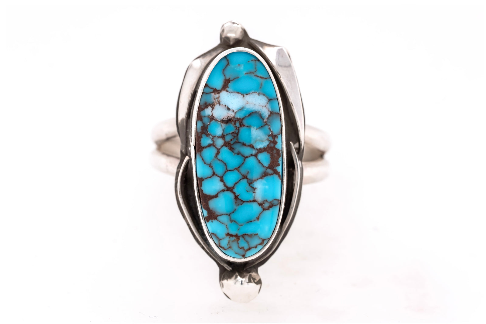 A sterling silver ring featuring a large, polished oval turquoise cabochon with a distinctive dark brown matrix pattern, set against a clean white background.