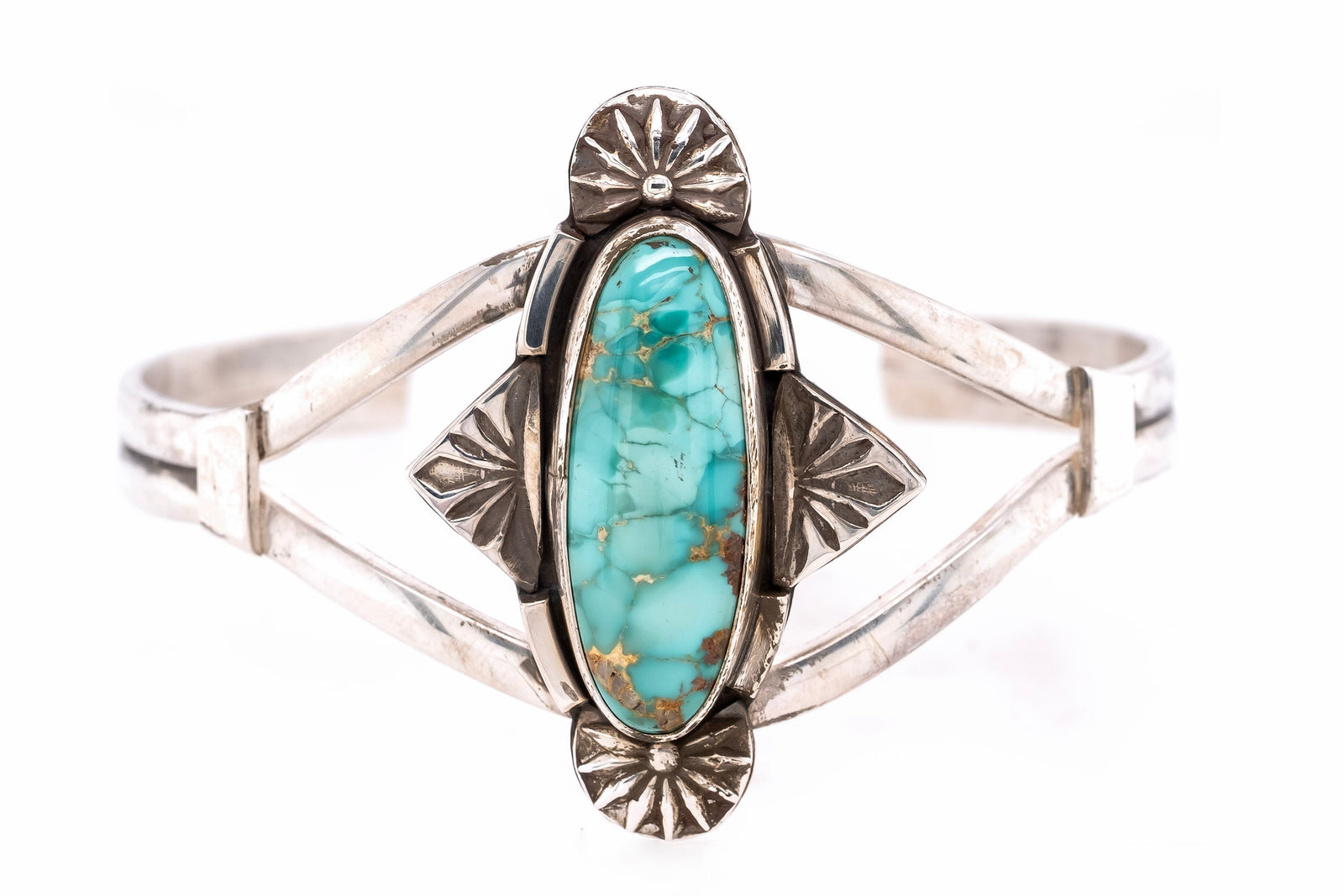 A sterling silver cuff bracelet featuring a prominent oval turquoise stone with brown matrix veining, accented by decorative sunburst and leaf motifs on a white background.