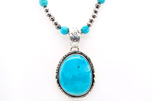 Turquoise pendant necklace with silver and blue beads on a white background