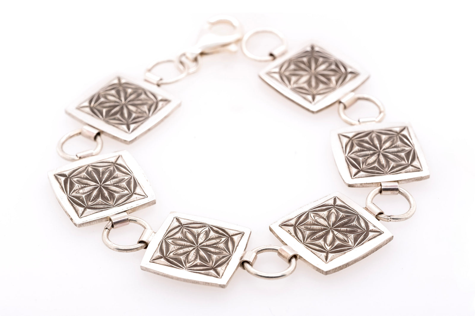 Silver bracelet with geometric designs on a white background
