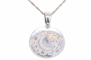 A silver round pendant necklace featuring an engraved crescent moon and stars, suspended from a silver chain against a white background.