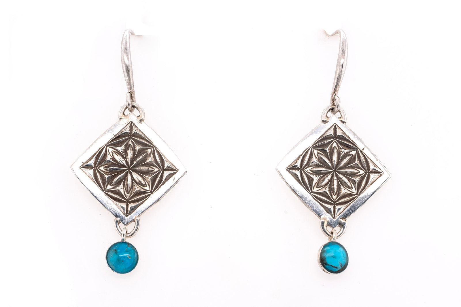 Silver earrings with geometric designs and turquoise stones on a white background