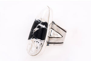 Handmade sterling silver ring with elongated White Buffalo stone in black and white, textured band, and triangular silver accents by Skylar Glandon